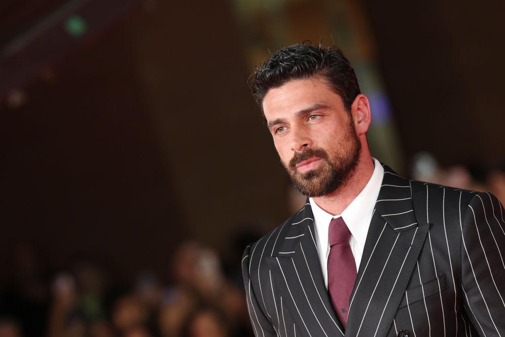 Michele Morrone îmbrăcat cu un costum negru cu dungi albe