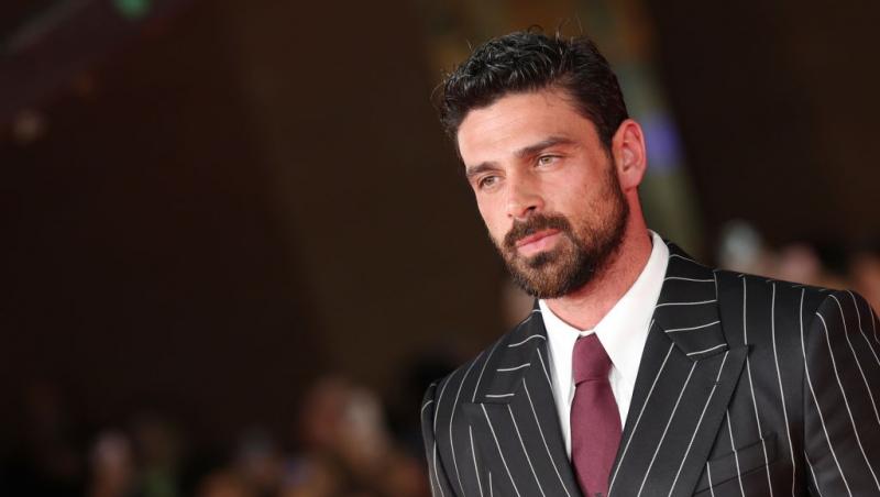 Michele Morrone îmbrăcat cu un costum negru cu dungi albe