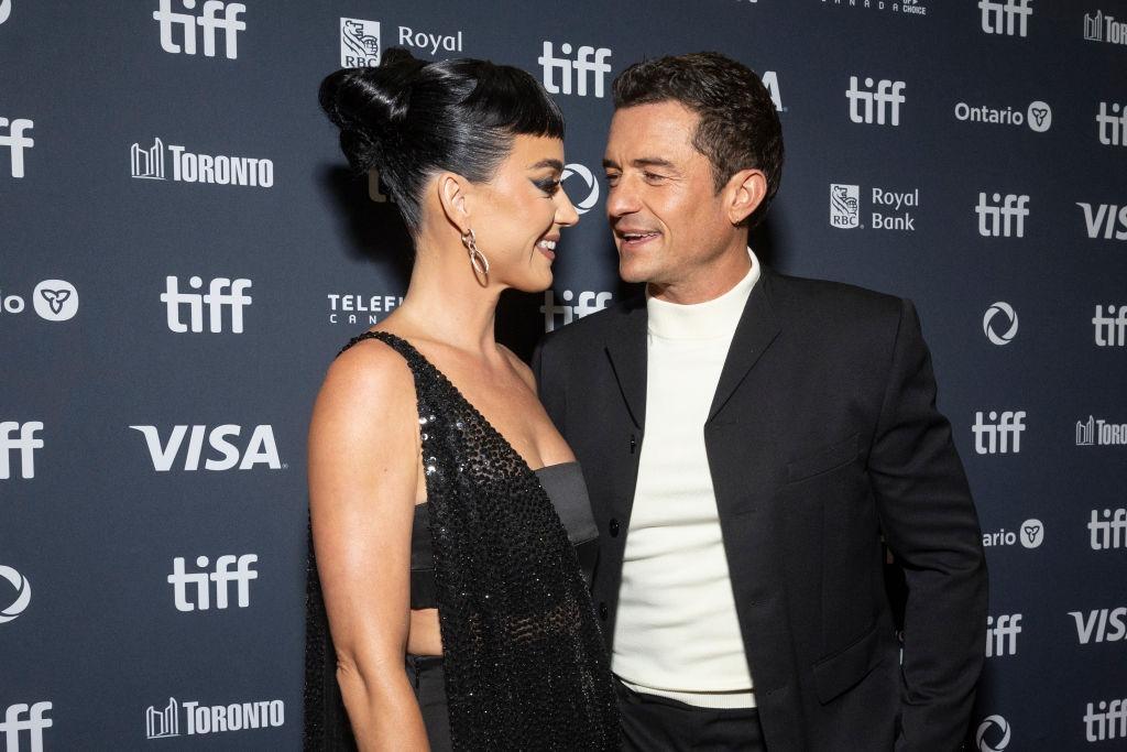 Katy Perry și Orlando Bloom îmbrăcați elegant, ținându-se de mână și zâmbind
