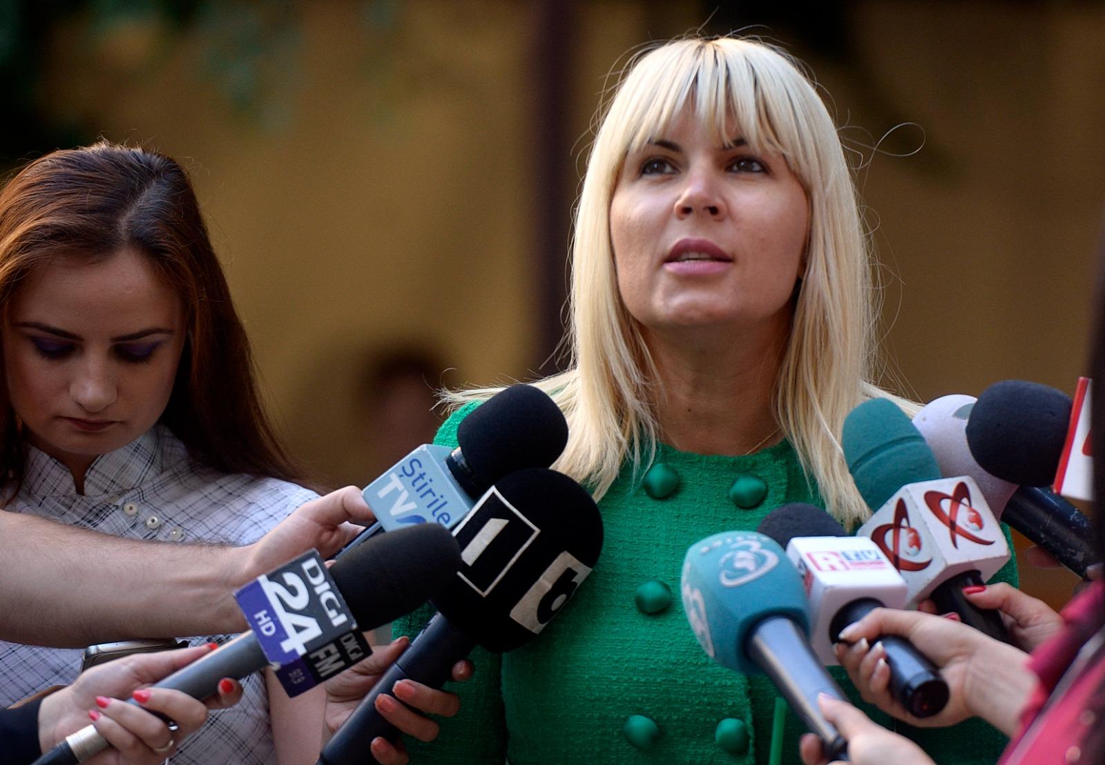 Elena Udrea îmbrăcată într-o ținută verde, înconjurată de reporteri