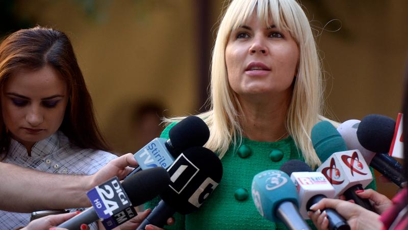 Elena Udrea îmbrăcată într-o ținută verde, înconjurată de reporteri
