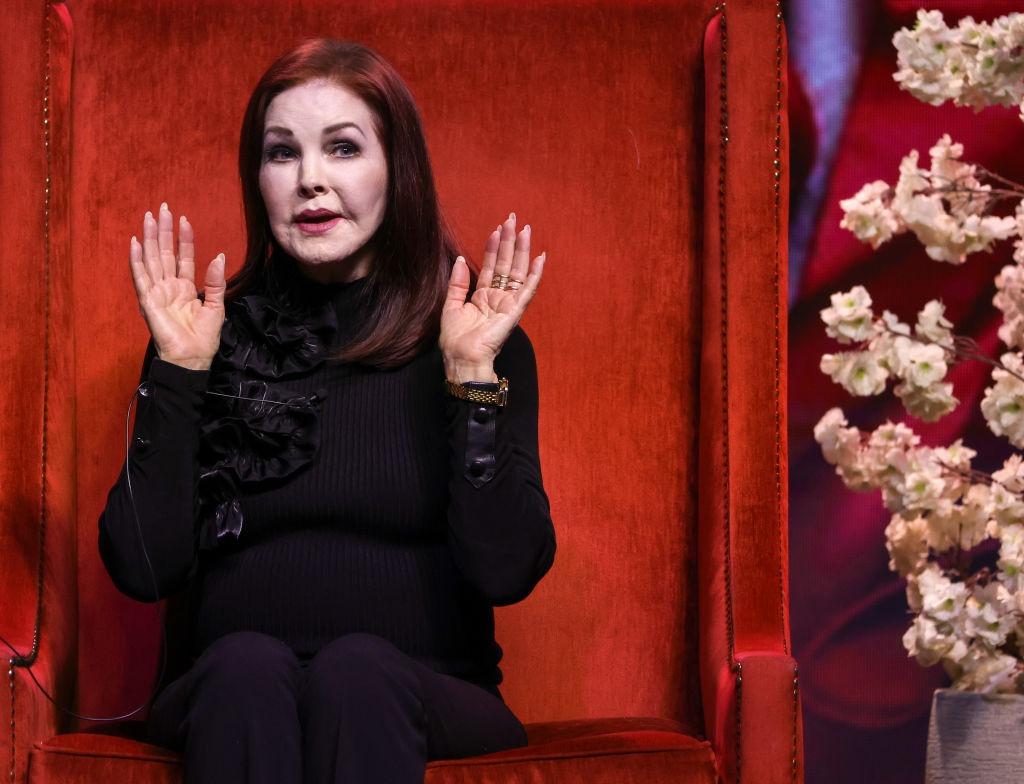 Priscilla Presley îmbrăcată într-o ținută complet neagră, vorbind