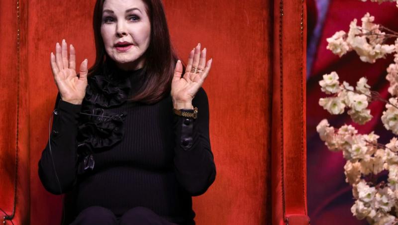 Priscilla Presley îmbrăcată într-o ținută complet neagră, vorbind