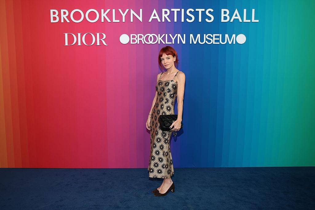 Lily Allen îmbrăcată într-o rochie maro cu detalii negre, lungă, fără mâneci