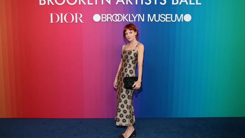 Lily Allen îmbrăcată într-o rochie maro cu detalii negre, lungă, fără mâneci