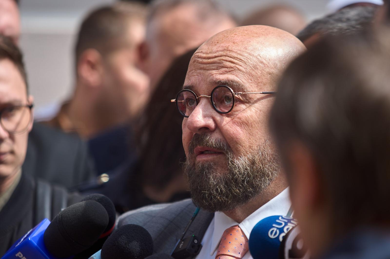 Piedone îmbrăcat cu un costum negru, la o conferință de presă