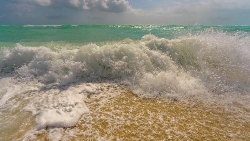 O plajă de pe litoralul românesc, inundată de valuri. Apa mării a trecut de primul rând de șezlonguri | VIDEO