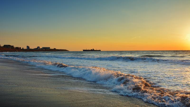 O plajă de pe litoralul românesc, inundată de valuri. Apa mării a trecut de primul rând de șezlonguri | VIDEO