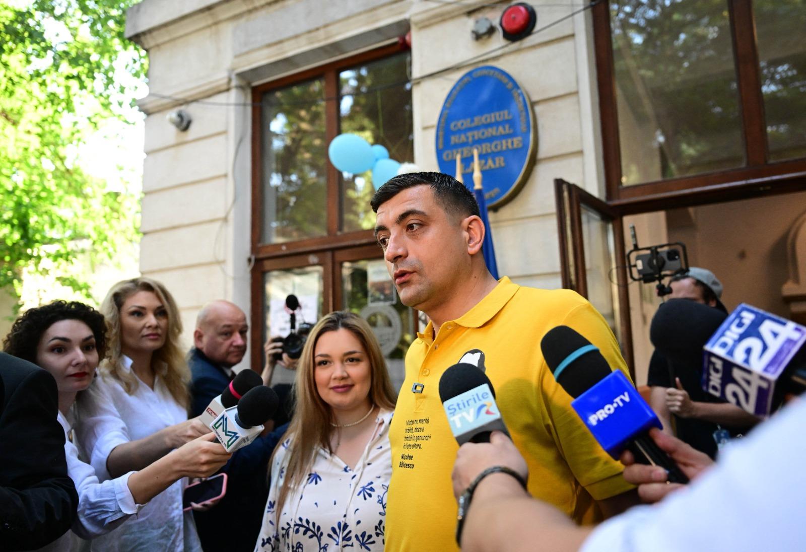 George Simion îmbrăcat cu un tricou galben, vorbind cu mai mulți jurnaliști