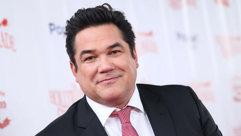 Dean Cain îmbrăcat într-un costum negru, accesorizat cu o cravată roșie