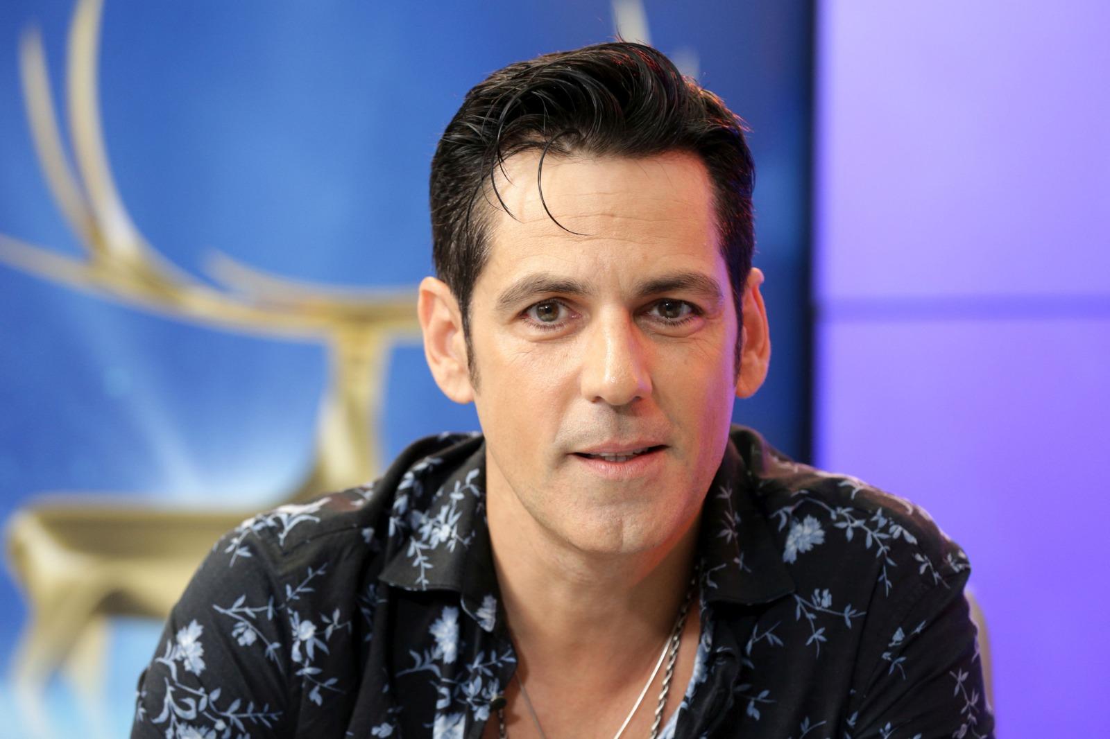 Ștefan Bănică Jr. îmbrăcat cu o cămașă neagră cu detalii albastre