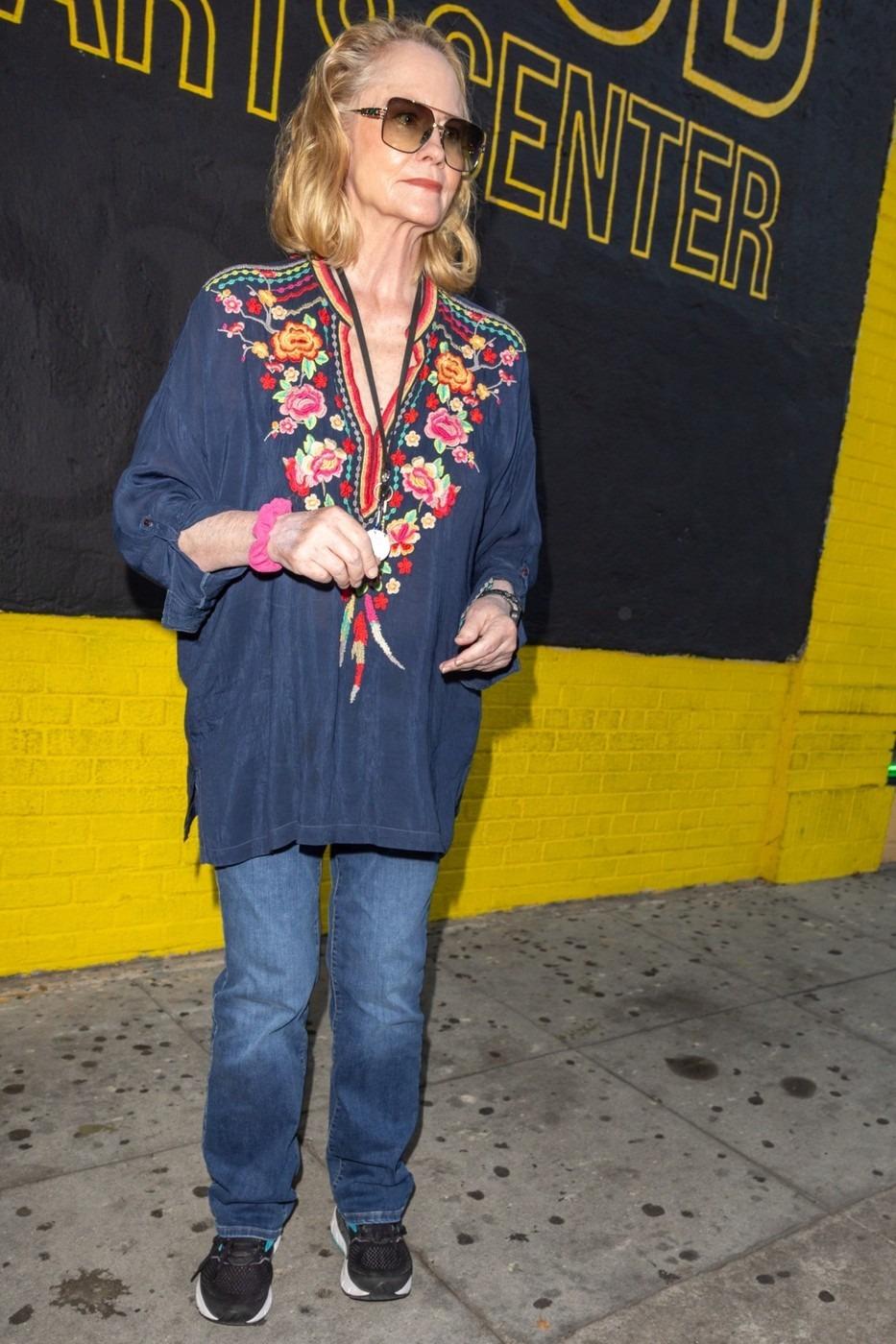 Cybill Shepherd îmbrăcată cu o bluză bleumarin cu detalii florale și pantaloni din denim