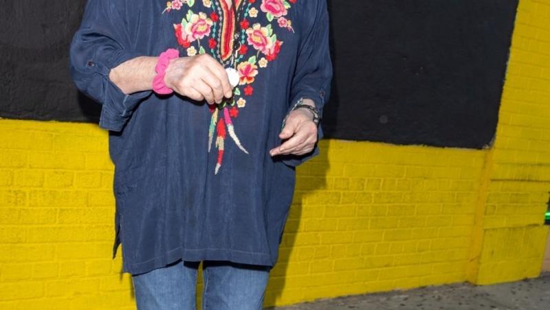 Cybill Shepherd îmbrăcată cu o bluză bleumarin cu detalii florale și pantaloni din denim