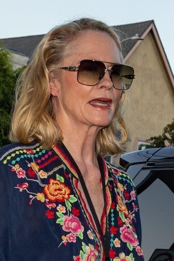 Cybill Shepherd îmbrăcată cu o bluză bleumarin cu detalii florale și pantaloni din denim