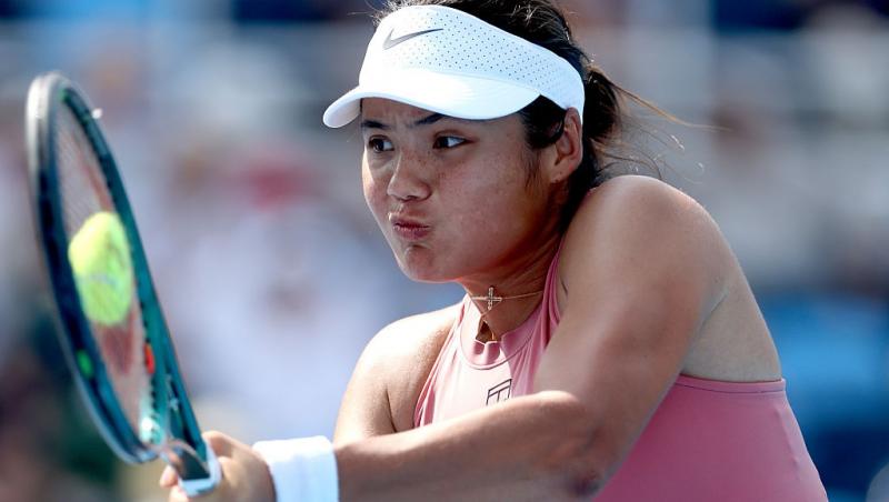 Emma Răducanu îmbrăcată într-o ținută sport roz și o șapcă albă, jucând tenis