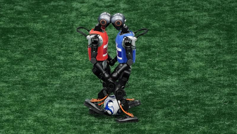 2 roboți care stau față în față pe un teren de fotbal