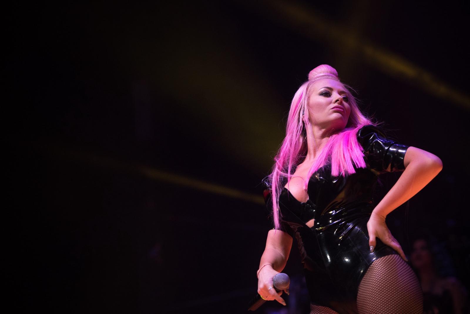 Delia îmbrăcată într-un body negru strălucitor, cântând pe scenă