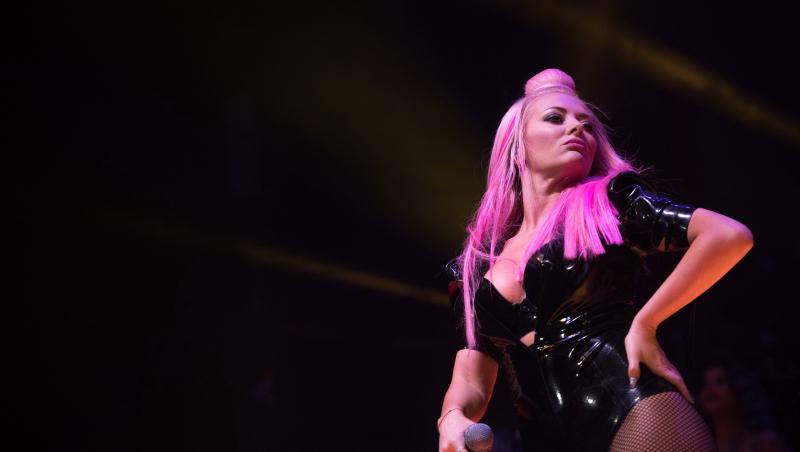 Delia îmbrăcată într-un body negru strălucitor, cântând pe scenă