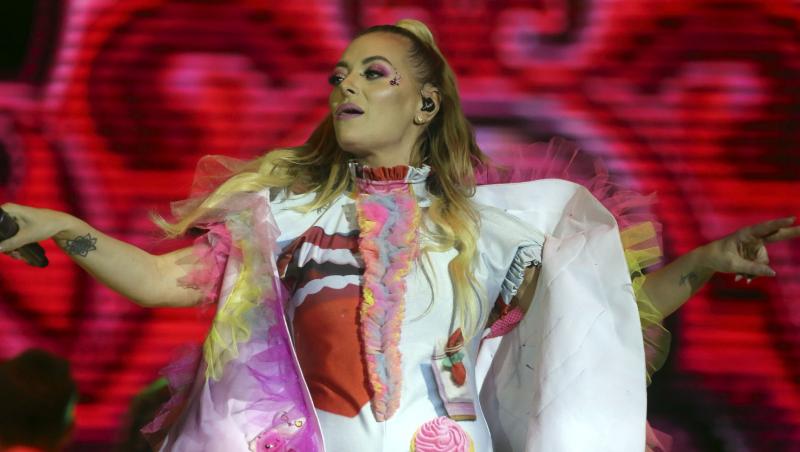 Delia îmbrăcată într-o ținută albă cu detalii colorate, dansând pe scenă