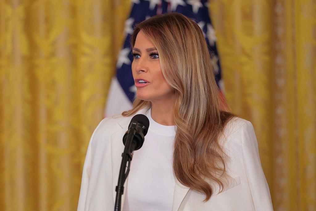 Melania Trump îmbrăcată cu o ținută albă, vorbind la microfon