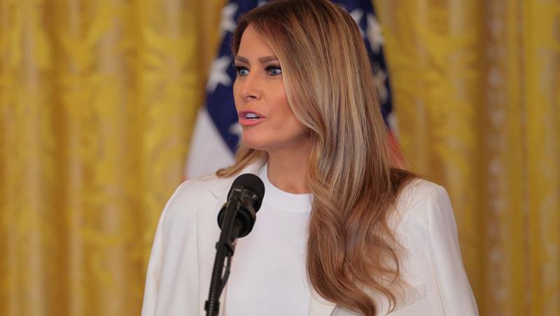 Melania Trump îmbrăcată cu o ținută albă, vorbind la microfon