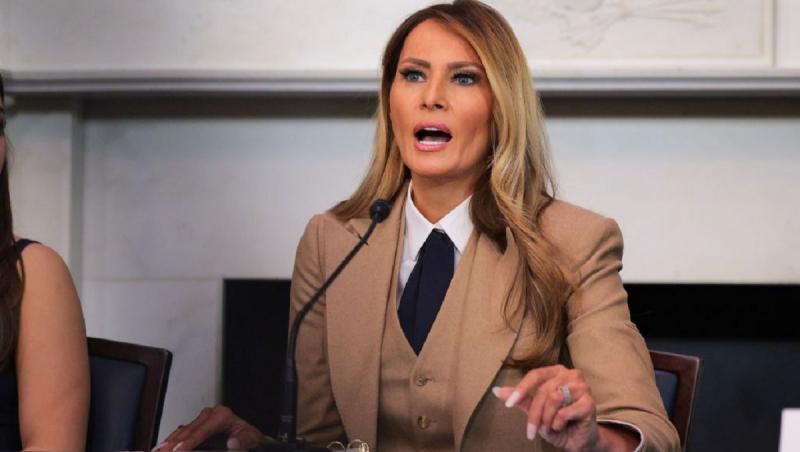 Melania Trump îmbrăcată cu un costum bej elegant, vorbind la microfon