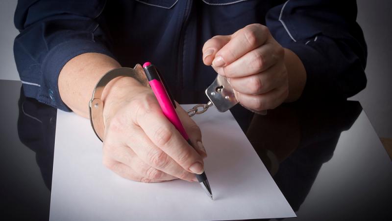 femeie încătușată care scrie pe o foaie