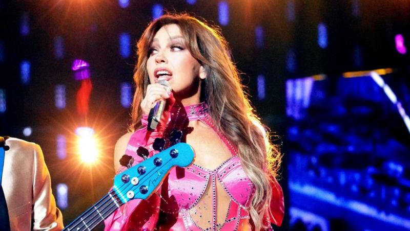 Thalia îmbrăcată într-o ținută roz sexy, cântând la microfon