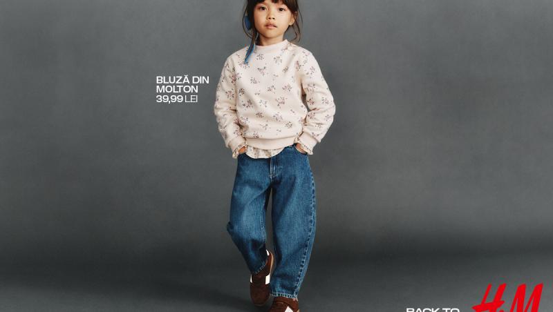 O fetiță îmbrăcată în blugi și o bluză albă