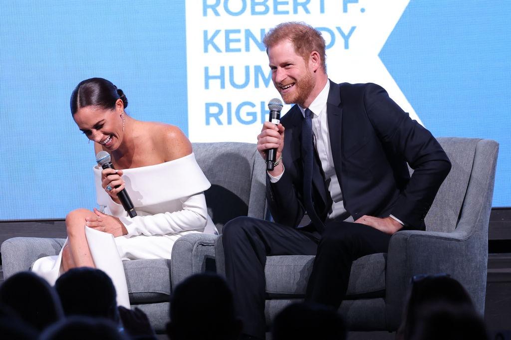 Meghan Markle alături de soțul ei, ambii îmbrăcați în ținute elegante, participând la o emisiune