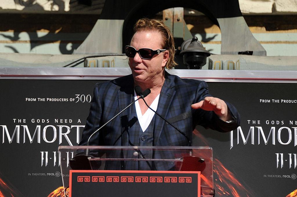 Mickey Rourke îmbrăcat într-un costum în carouri, vorbind la microfon