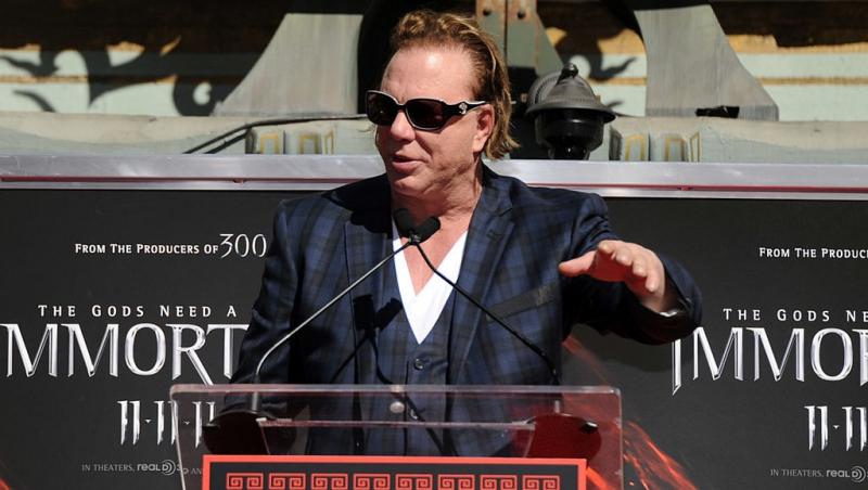 Mickey Rourke îmbrăcat într-un costum în carouri, vorbind la microfon