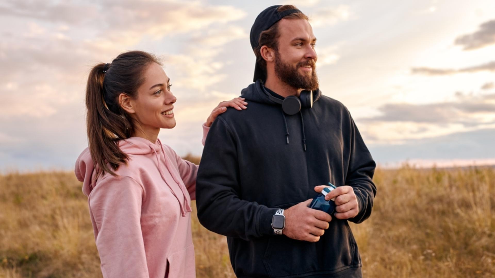 O femeie și un bărbat care poartă hanorace, unul roz și unul negru