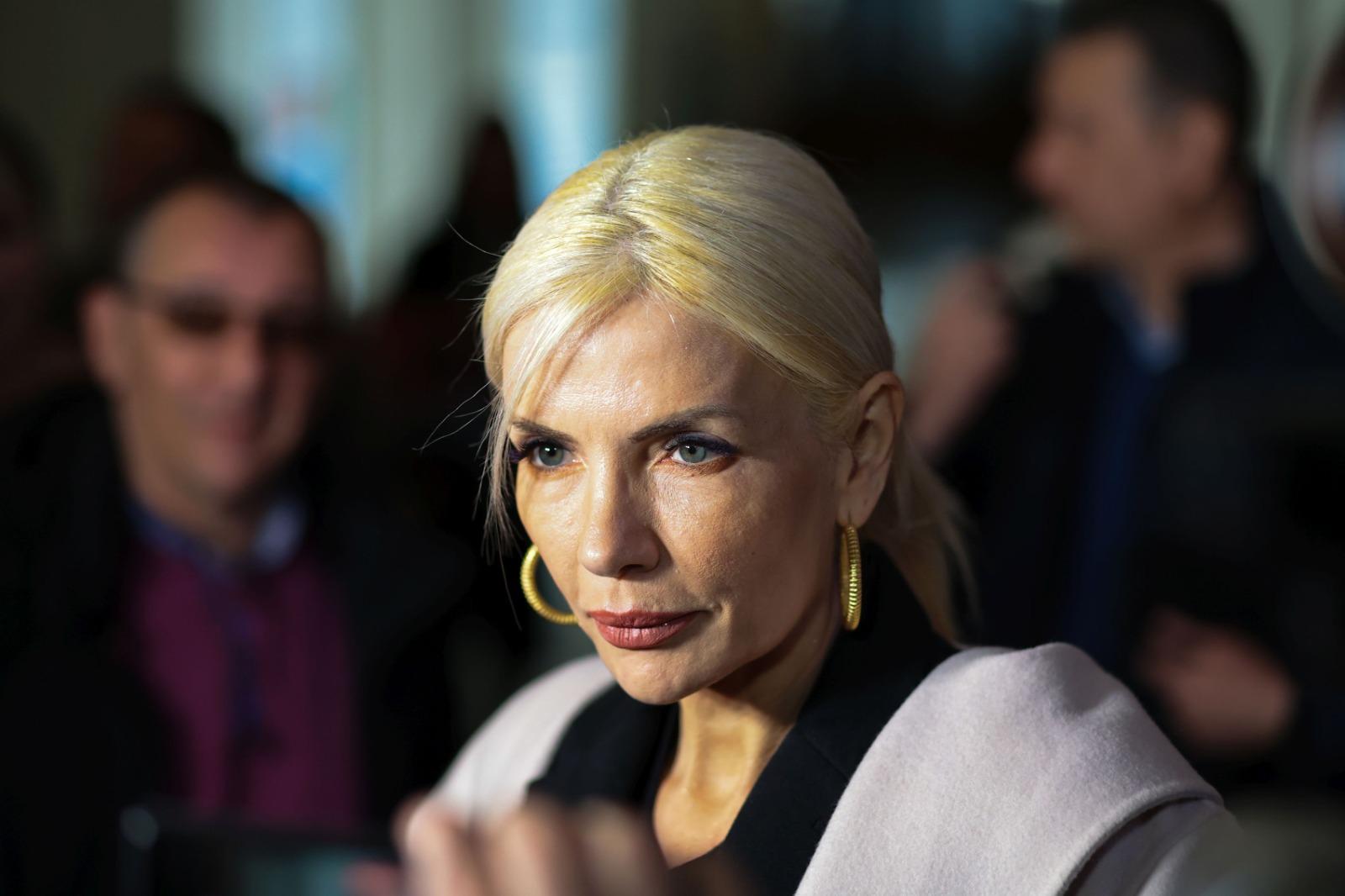 Laura Vicol îmbrăcată cu un palton gri, peste o cămașă neagră