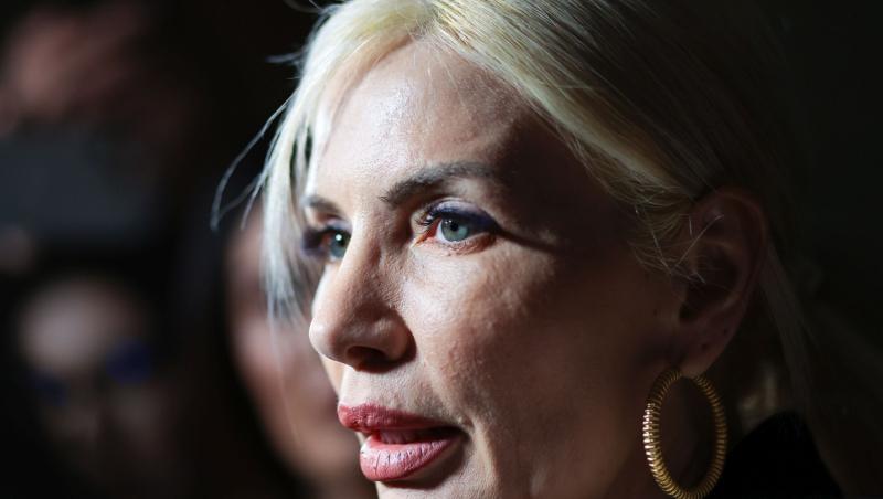 Laura Vicol îmbrăcată cu un palton gri, peste o cămașă neagră