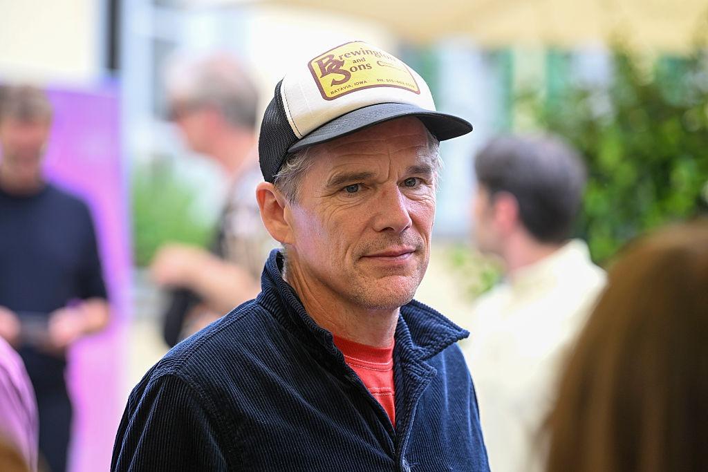 Ethan Hawke îmbrăcat cu o jachetă bleumarin peste un tricou roșu