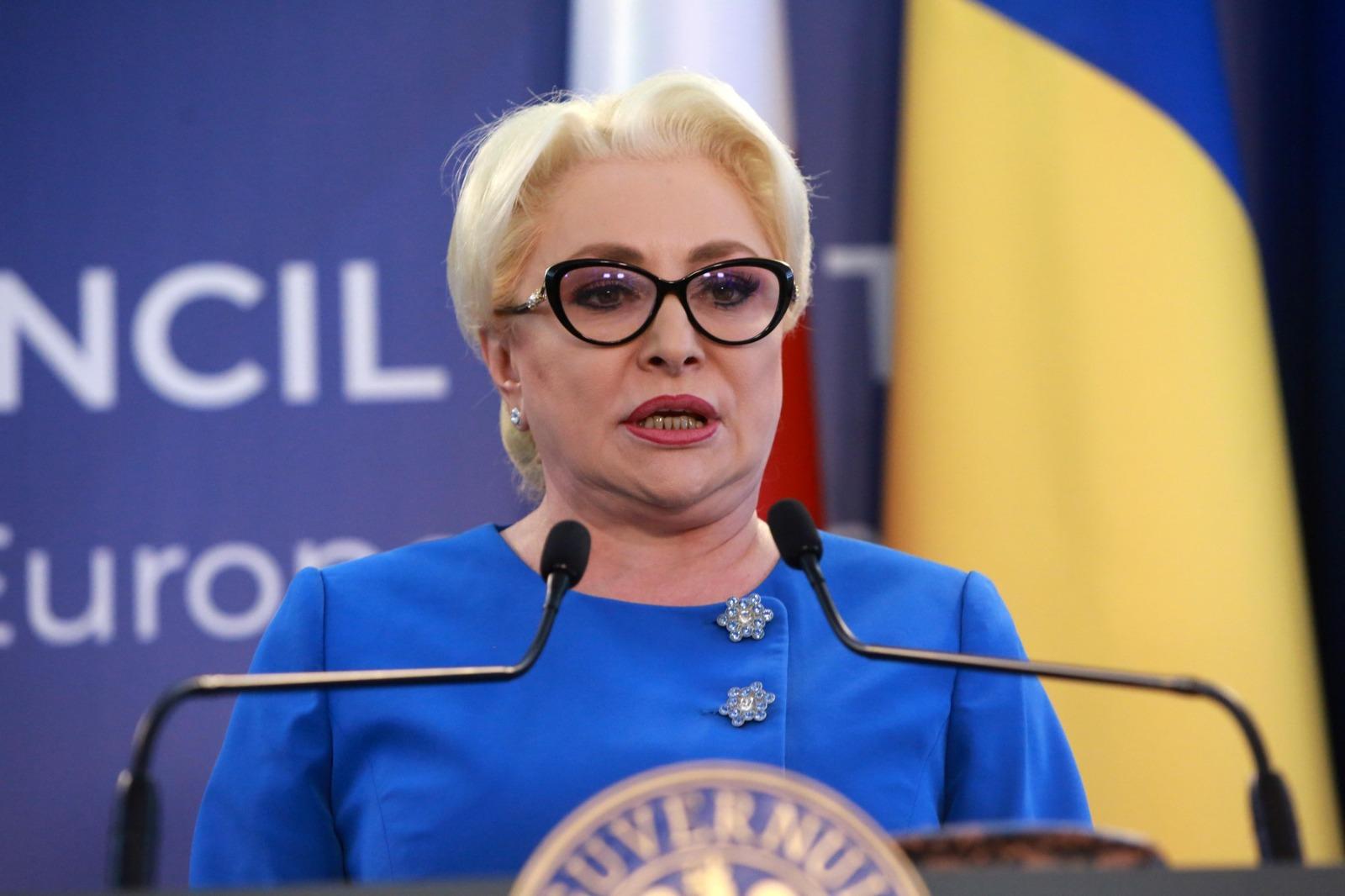 Viorica Dăncilă îmbrăcată într-o ținută albastră, vorbind la microfon