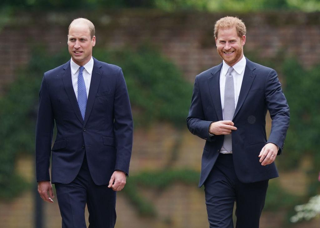 Prințul Harry și Prințul William îmbrăcați în costume bleumarin, mergând