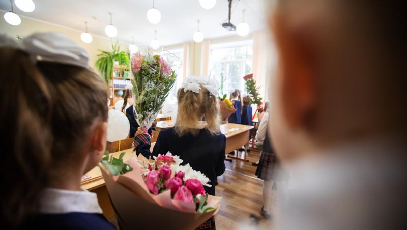 imagine cu mai multi elevi care tin buchete de flori in mana