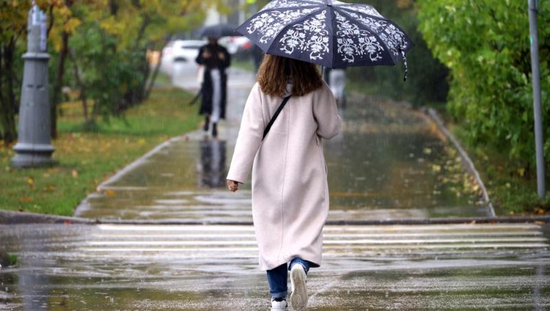 imagine cu o femeie imbracata de toamna care se plimba prin ploaie