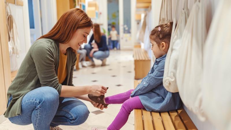 mamă care &icirc;și &icirc;ncalță fetițas