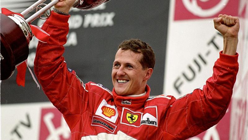 Michael Schumacher &icirc;n costum ferrari sărbătorind cu un trofeu &icirc;n m&acirc;nă
