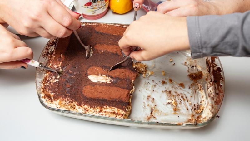 m&acirc;ini care iau cu lingura dintr-o tavă de tiramisu