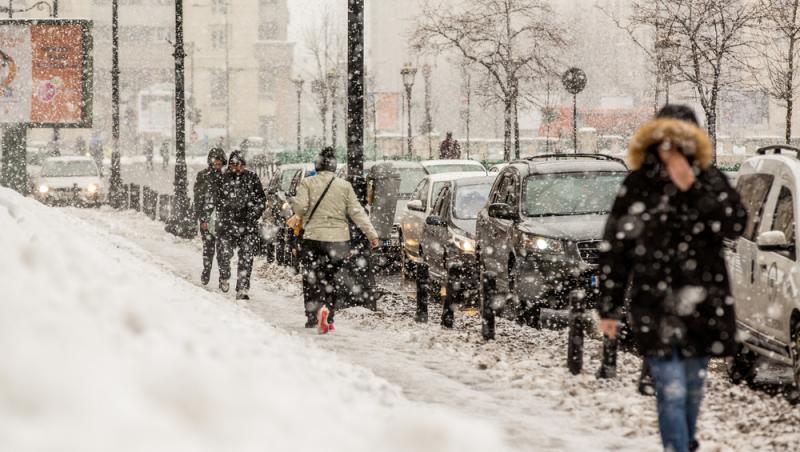 oameni pe stradă &icirc;n timpul unui viscol iarna