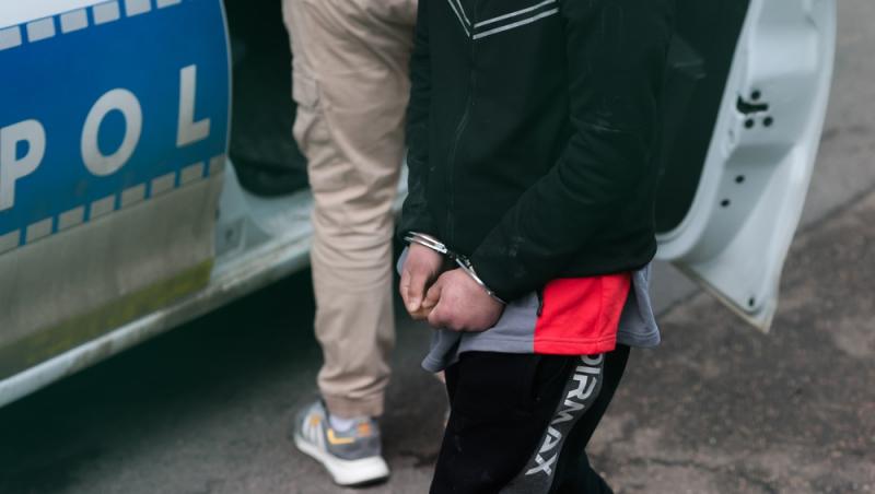 t&acirc;năr cu cătușe l&acirc;ngă mașina poliției