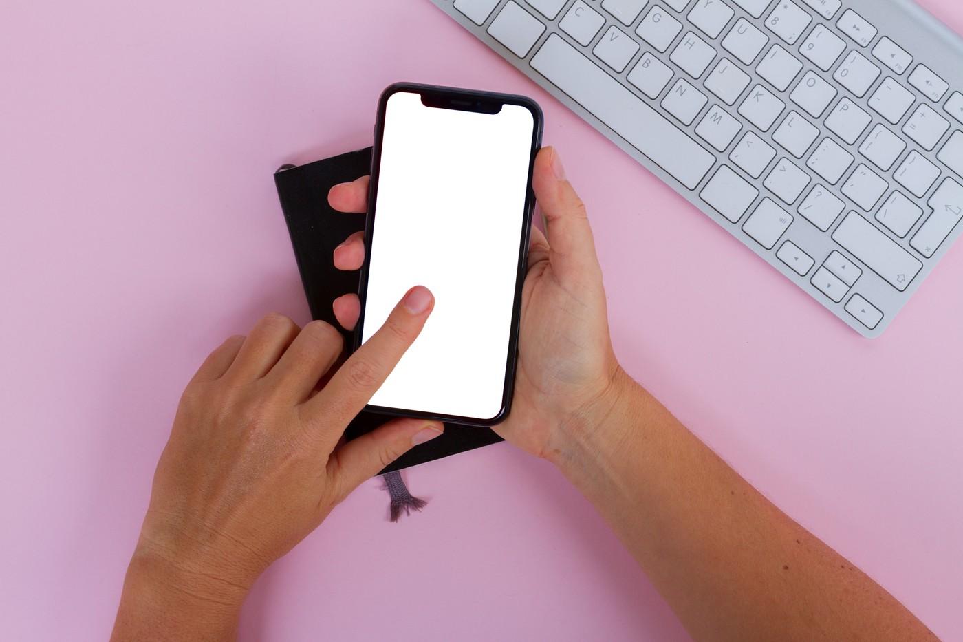 Două mâini ținând și atingând noul telefon mobil iPhone X cu