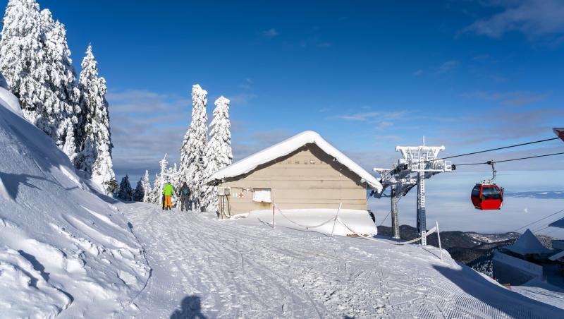 Peisaj de pe v&acirc;rful muntelui Postăvaru, cu p&acirc;rtii de schi și telecabină, &icirc;n Poiana Brașov, Rom&acirc;nia
