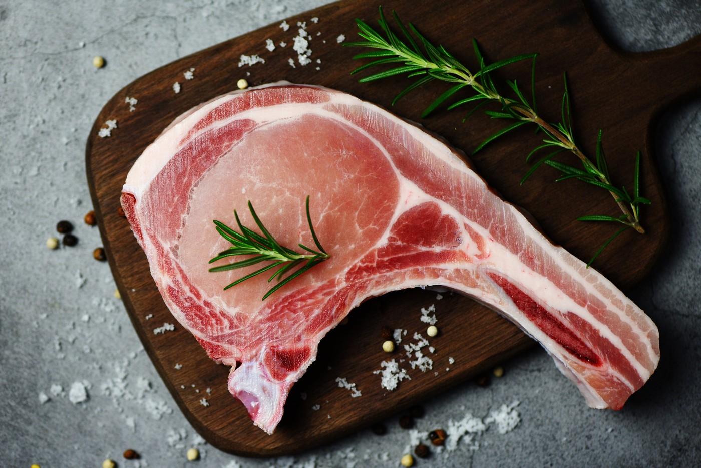 Cotlete de porc crude, proaspete, cu ierburi și condimente / carne de porc proaspătă, feliată, pe fundal negru