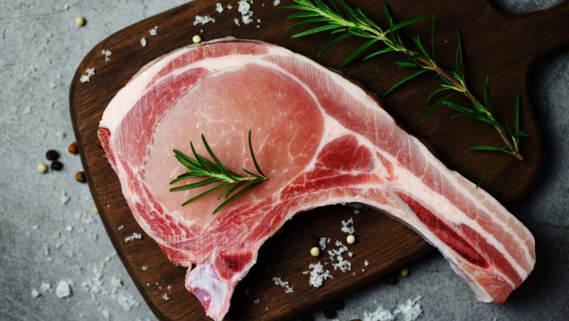 Cotlete de porc crude, proaspete, cu ierburi și condimente / carne de porc proaspătă, feliată, pe fundal negru