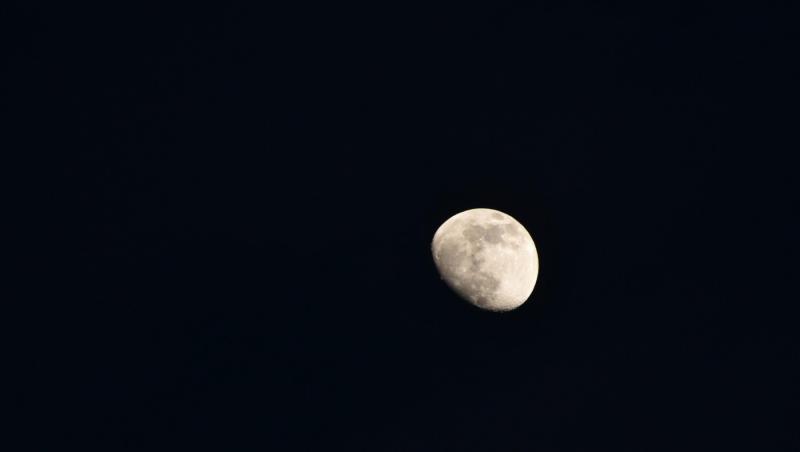Lună plină galben-strălucitoare, plutind pe cer, pe fundal nocturn